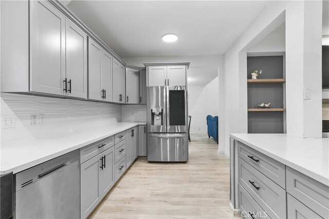 kitchen featuring gray cabinetry, backsplash, built in shelves, light hardwood / wood-style floors, and stainless steel appliances