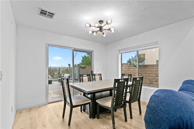 dining room featuring a chandelier, a textured ceiling, and light hardwood / wood-style flooring