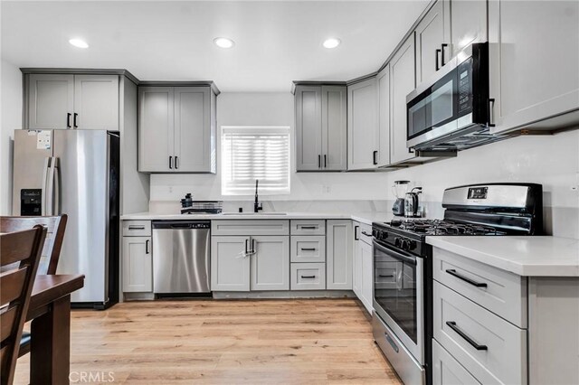 kitchen with appliances with stainless steel finishes, sink, and gray cabinetry