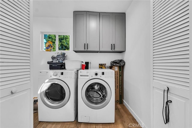 laundry area with separate washer and dryer, light hardwood / wood-style flooring, and cabinets