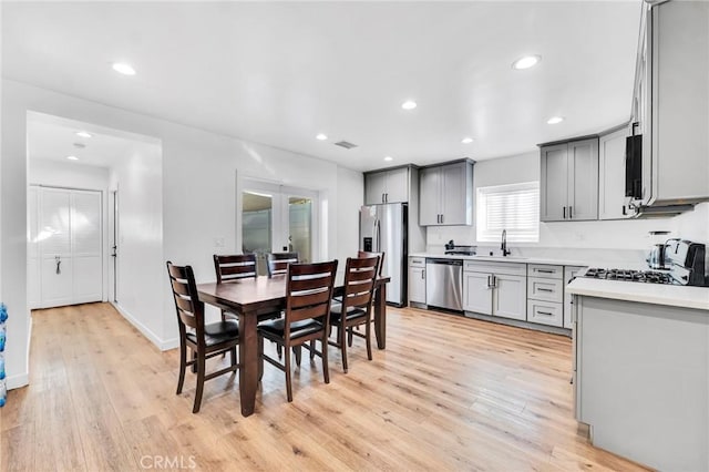 dining room with sink, french doors, and light wood-type flooring