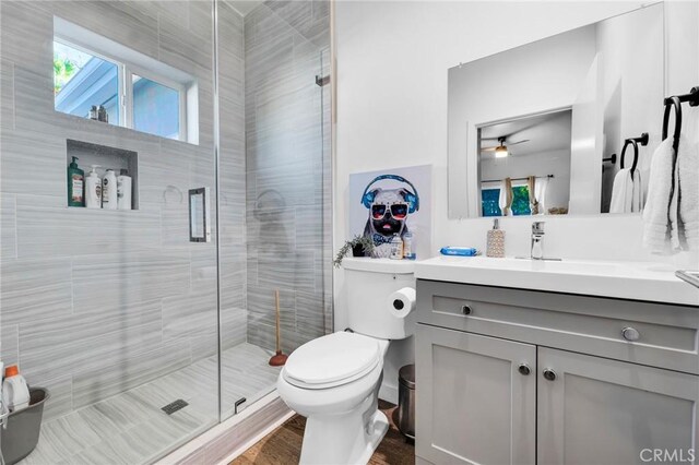 bathroom featuring a shower with door, vanity, hardwood / wood-style floors, and toilet