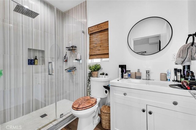 bathroom with a shower with door, vanity, and toilet