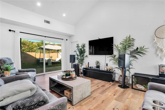 living room with high vaulted ceiling and light hardwood / wood-style floors