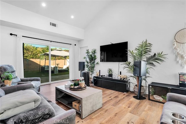 living room featuring high vaulted ceiling and light wood-type flooring