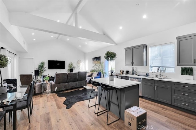 kitchen with gray cabinets, a kitchen island, sink, a kitchen bar, and beam ceiling