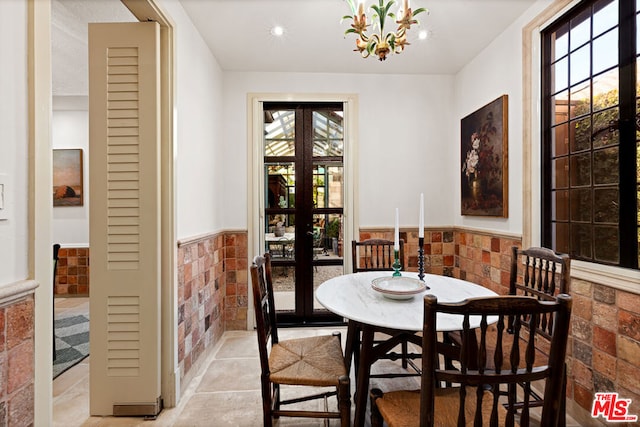 dining space featuring tile walls, a notable chandelier, a wealth of natural light, and french doors