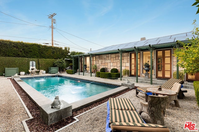 view of swimming pool with a patio area, pool water feature, and french doors