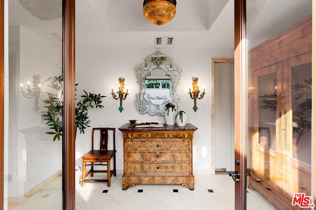 corridor with light tile patterned floors and a raised ceiling