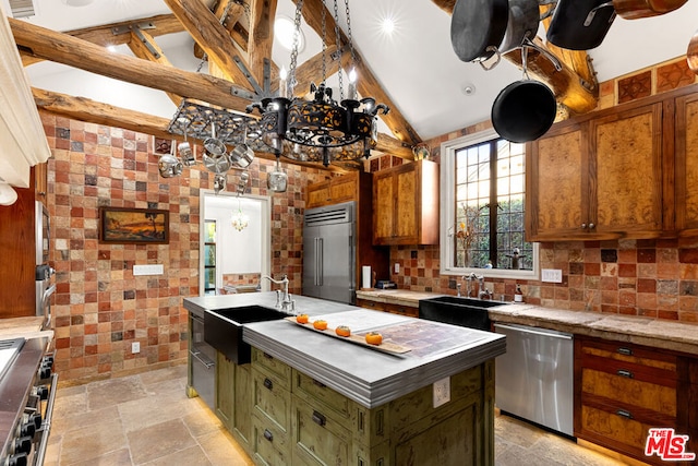 kitchen featuring beam ceiling, sink, a center island with sink, and premium appliances