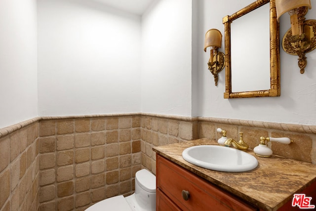 bathroom featuring vanity, tile walls, and toilet