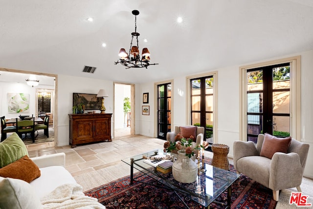 living room with vaulted ceiling, an inviting chandelier, and french doors