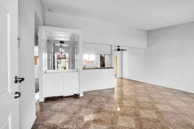 unfurnished living room featuring a textured ceiling and ceiling fan