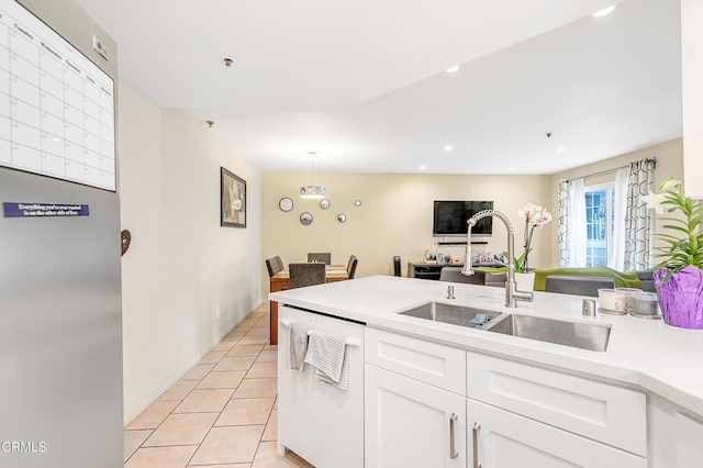 kitchen with dishwasher, hanging light fixtures, sink, light tile patterned floors, and white cabinetry