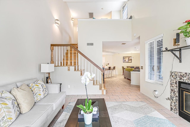 living room featuring light tile patterned floors, a fireplace, and a high ceiling