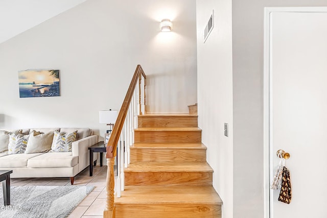 stairway featuring tile patterned flooring and lofted ceiling