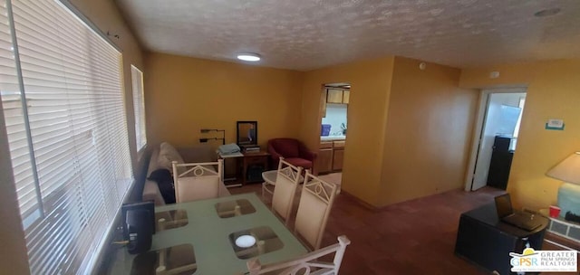 carpeted dining room with a textured ceiling