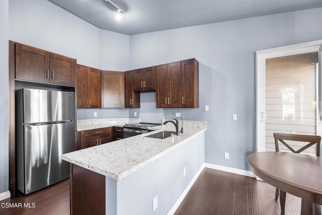 kitchen featuring light stone countertops, appliances with stainless steel finishes, dark brown cabinets, dark wood-type flooring, and sink