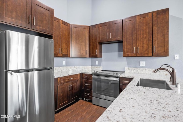 kitchen with light stone countertops, sink, appliances with stainless steel finishes, and dark wood-type flooring