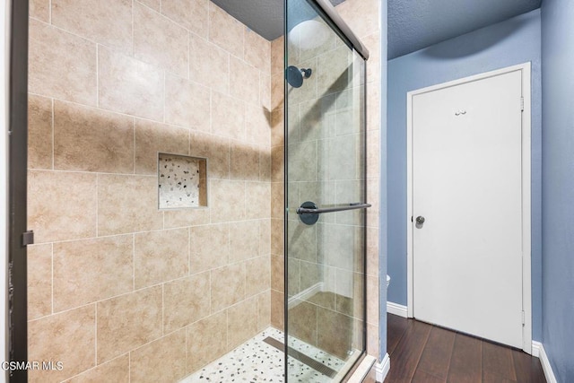 bathroom with a textured ceiling, hardwood / wood-style flooring, and an enclosed shower