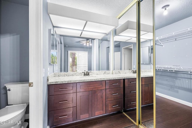 bathroom with hardwood / wood-style floors, vanity, toilet, and ceiling fan