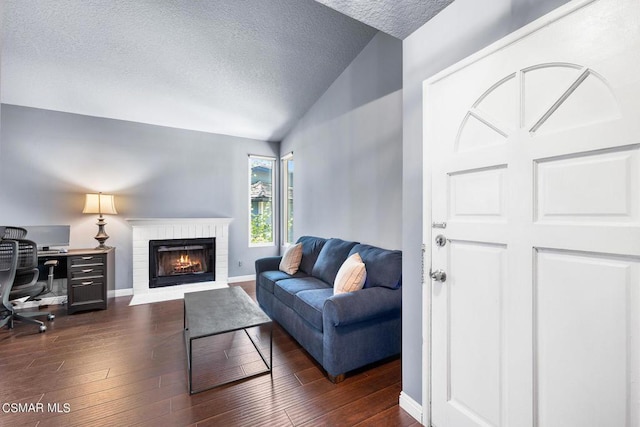 living room with a textured ceiling, lofted ceiling, dark wood-type flooring, and a brick fireplace