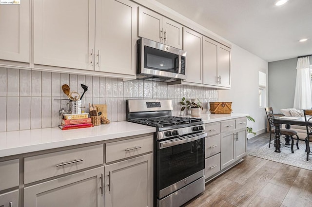 kitchen featuring appliances with stainless steel finishes, decorative backsplash, light hardwood / wood-style floors, and gray cabinets