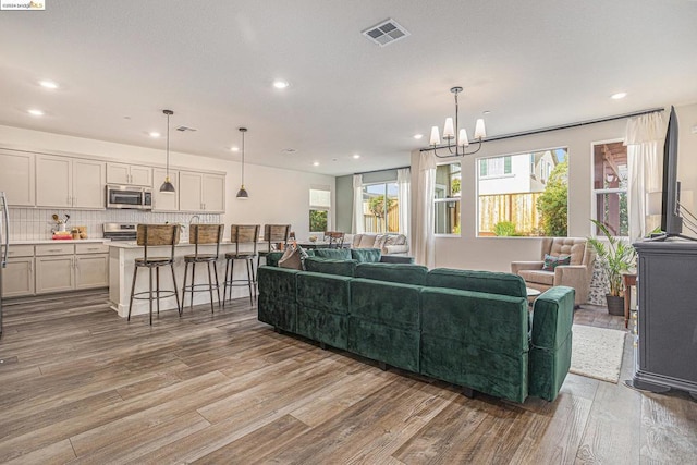 living room featuring a healthy amount of sunlight, a chandelier, and light hardwood / wood-style floors