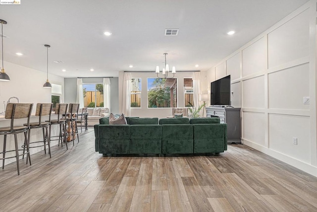 living room featuring light wood-type flooring and a notable chandelier