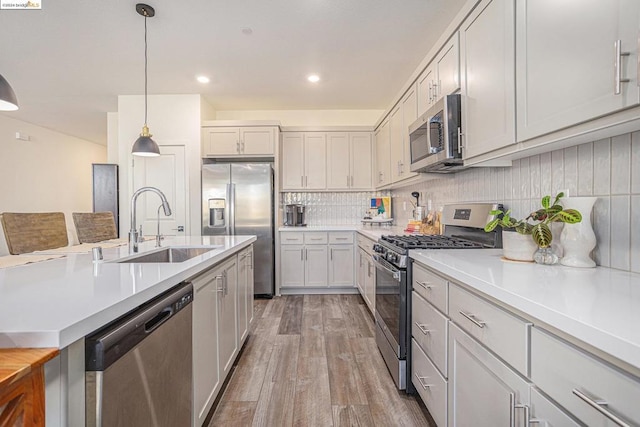 kitchen featuring decorative light fixtures, sink, white cabinetry, hardwood / wood-style flooring, and stainless steel appliances