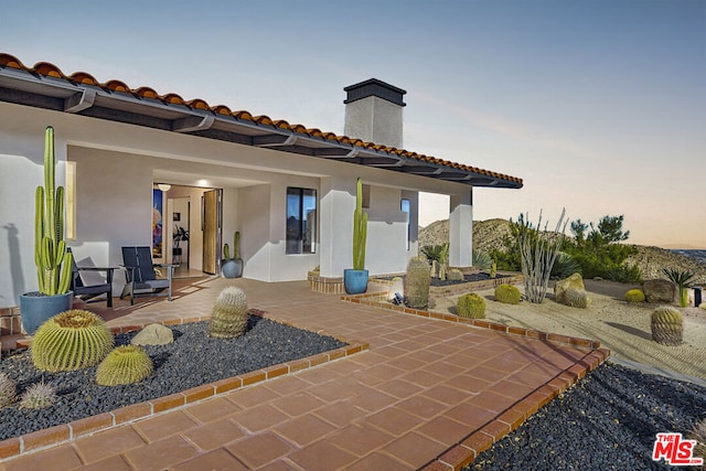 back house at dusk with a patio