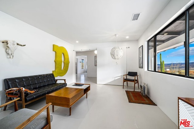 living room featuring a chandelier and concrete flooring