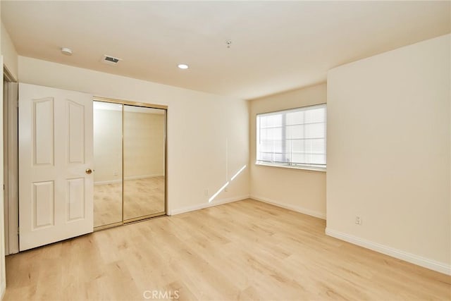 unfurnished bedroom with light hardwood / wood-style flooring and a closet