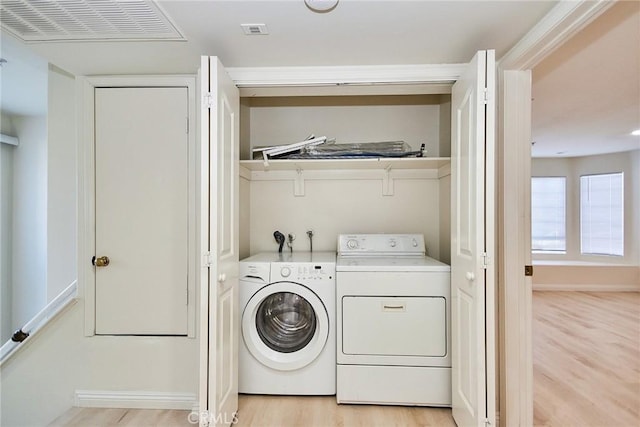 clothes washing area with washer and dryer and light hardwood / wood-style flooring