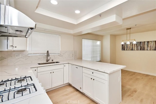 kitchen featuring sink, hanging light fixtures, ventilation hood, kitchen peninsula, and white dishwasher