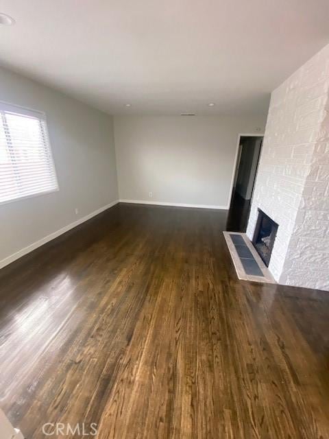 unfurnished living room featuring dark hardwood / wood-style floors and a large fireplace