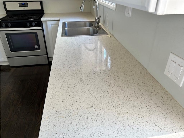 kitchen with white cabinets, gas range, and sink