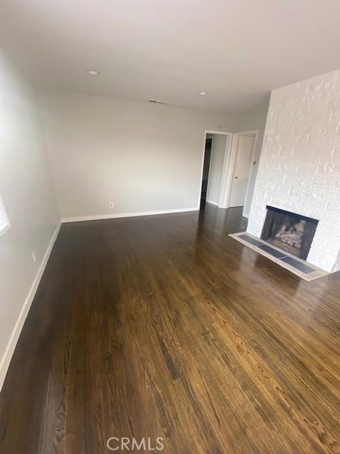 unfurnished living room with a fireplace and dark wood-type flooring