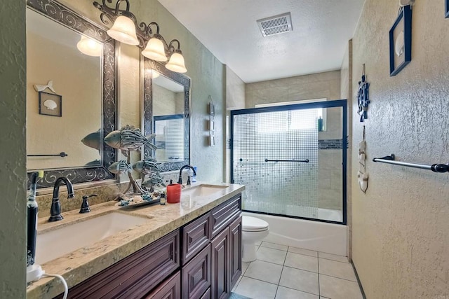 full bathroom with tile patterned floors, vanity, bath / shower combo with glass door, and toilet