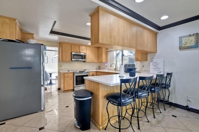 kitchen featuring sink, ornamental molding, light brown cabinetry, appliances with stainless steel finishes, and kitchen peninsula