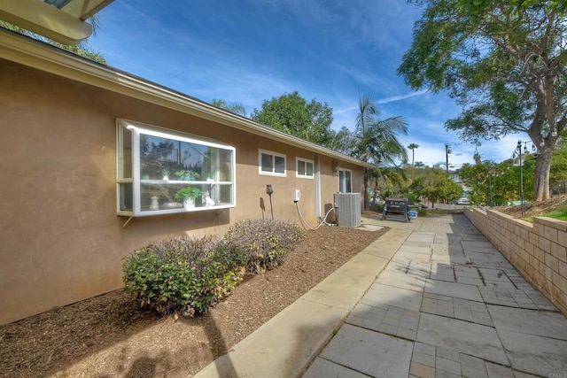 view of side of property featuring a patio area and cooling unit