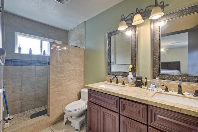 bathroom featuring tile patterned flooring, vanity, toilet, and tiled shower