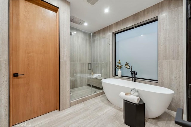 bathroom featuring separate shower and tub and tile walls