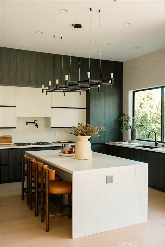 kitchen featuring sink, hanging light fixtures, dark brown cabinets, a kitchen island, and a breakfast bar area