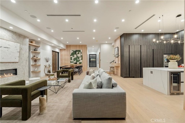 living room featuring a fireplace, wine cooler, and light hardwood / wood-style flooring