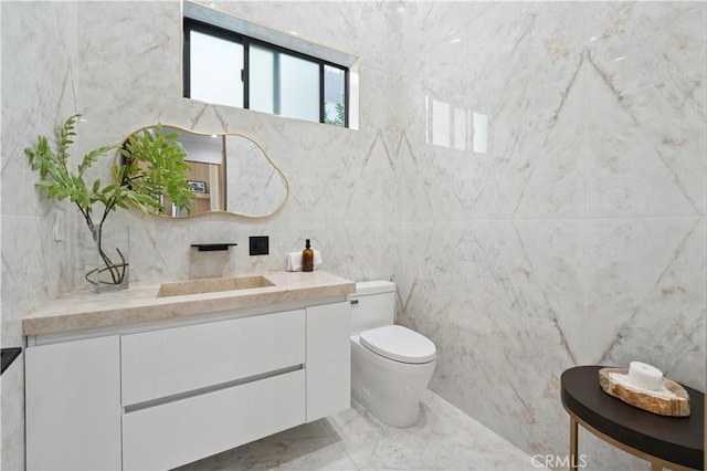 bathroom featuring vanity, tile walls, and toilet