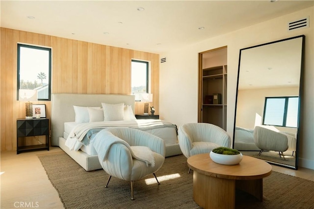 bedroom with wood walls and a walk in closet