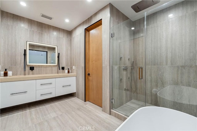 bathroom featuring vanity, separate shower and tub, and tile walls