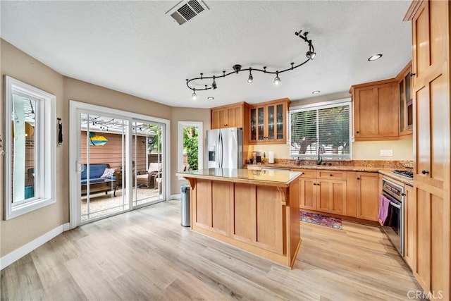 kitchen with sink, a kitchen island, stainless steel appliances, and light hardwood / wood-style floors