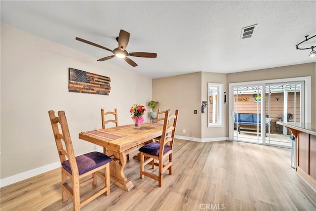 dining area featuring ceiling fan, a textured ceiling, and light wood-type flooring